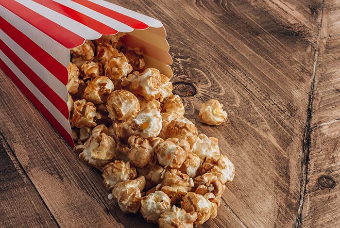 A bucket of flavored popcorn splayed on a wooden surface.