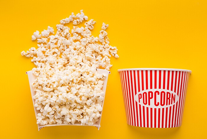 A bucket of popcorn cut in half to show its contents.